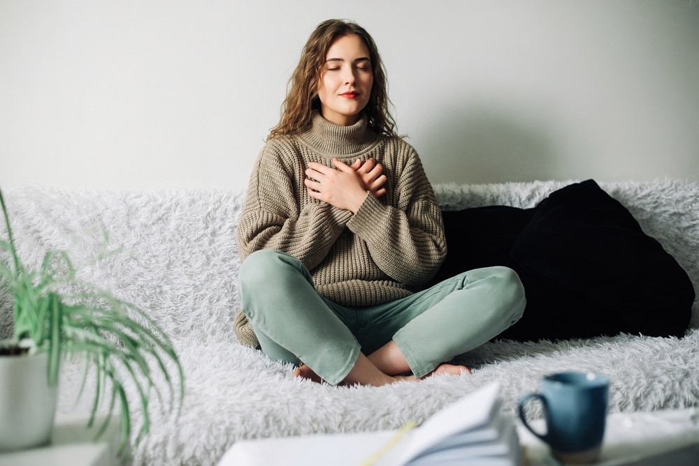 Relaxation,techniques:,woman,practicing,pranayama,in,lotus,position,on,bed,