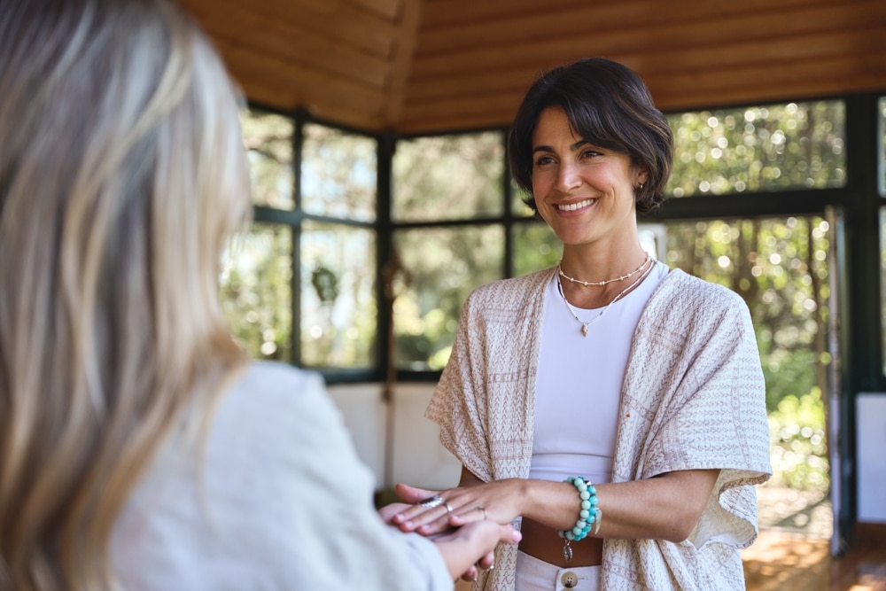 Happy,female,holistic,teacher,holding,hands,of,woman,during,spiritual